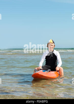 Porträt des jungen Nipper (Kind Surf Life Savers) rittlings auf Surfbrett, Altona, Melbourne, Australien Stockfoto