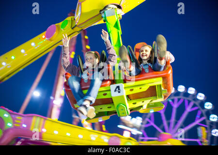 Schwester und Bruder Mitte Luft auf Festplatz fahren in der Nacht Stockfoto