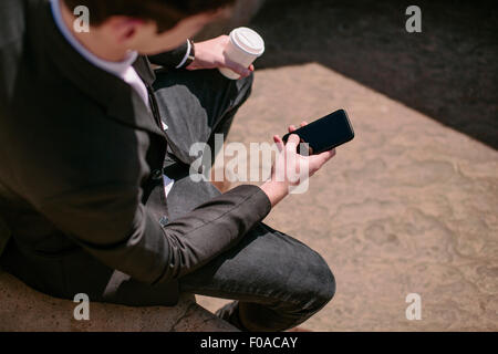 Über die Schulter Blick jungen Geschäftsmann Smartphone Texte lesen Stockfoto