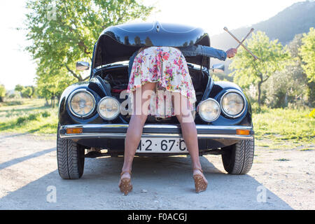 Reife Frau beugte sich über Autos, Blick in Motorhaube Stockfoto