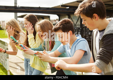 Fünf Mädchen und jungen im Stadion stehen Smartphones lesen Stockfoto