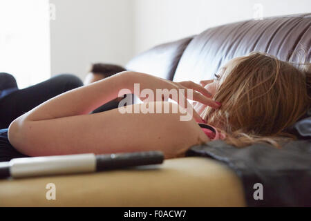 Mädchen und Bruder vor dem Fernseher vom Sofa aus Stockfoto