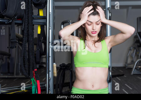 Porträt der jungen Frau hält ihren Kopf in Händen in der Turnhalle Stockfoto