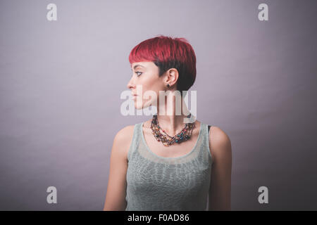 Studio-Porträt der jungen Frau mit kurzen rosa Haaren über die Schulter schauen Stockfoto