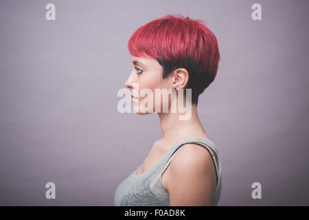 Profil-Studio-Porträt der jungen Frau mit kurzen rosa Haaren mit Händen auf Wangen Stockfoto