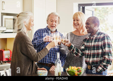 Senioren Freunde Toasten mit Wein in Küche Stockfoto