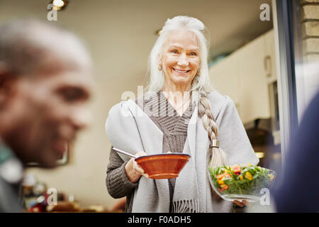 Ältere Frau, die Schüsseln mit Salat außerhalb