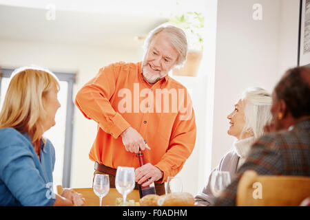 Senior woman Eröffnung Wein mit Freunden Stockfoto