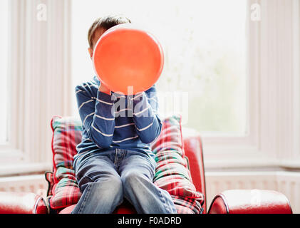 Kleiner Junge hält Ballon vor Gesicht Stockfoto