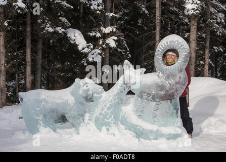 Junge Frau, die durch Eis-Skulptur Stockfoto