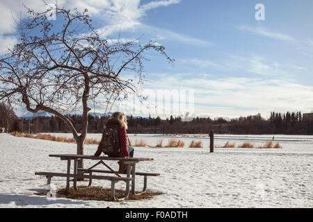 Junge Frau sitzt auf Picknickbank, Anchorage, Alaska Stockfoto