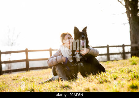 Porträt von Mitte erwachsenen Frau sitzt mit ihrem Hund im Feld Stockfoto