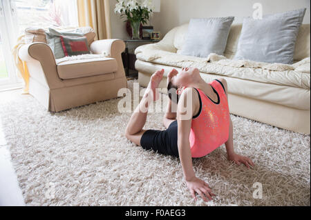 Mädchen üben Gymnastik bücken nach hinten auf Wohnzimmer Teppich Stockfoto