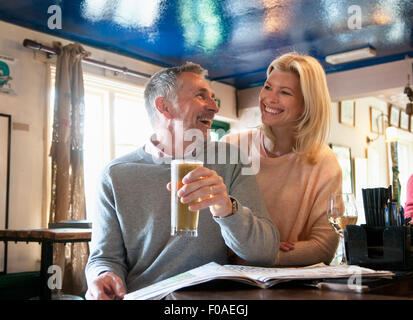 Paar Lachen und Zeitunglesen im pub Stockfoto
