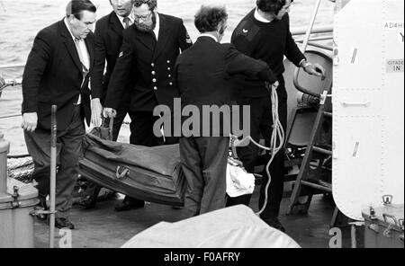 AJAXNETPHOTO. 16. August 1979. PLYMOUTH, ENGLAND. -FASTNET END - BESTATTER UND CREW ENTFERNEN DEN KÖRPER EINES OPFERS DER YACHT RACE KATASTROPHE AUS DER NIEDERLÄNDISCHEN MARINE FREGATTE OVERIJSSEL, WENN DAS SCHIFF IN DEVONPORT ANGEDOCKT.  FOTO: JONATHAN EASTLAND/AJAX. REF: 791608 XA Stockfoto