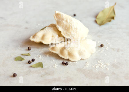 Rohe gefrorenen Teig Knödel mit Gewürzen hautnah über weißem rustikalen Stein Hintergrund Stockfoto