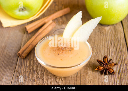 Frische hausgemachte Apfelmus mit Zimt (Gewürze), Löffel und Äpfel auf Holztisch in der Nähe (Apfelmus, Mousse, Babynahrung, Soße) Stockfoto