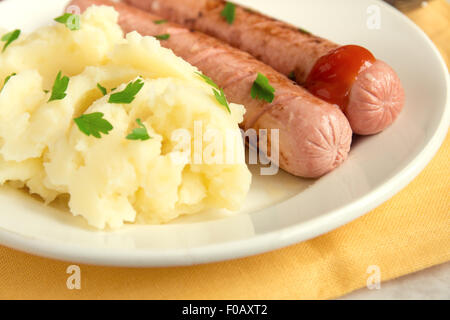 Kartoffelpüree und Würstchen mit Petersilie und Ketchup auf weißen Teller Stockfoto