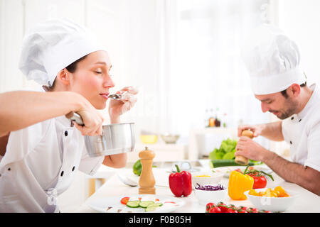 Blick auf eine junge attraktive Profi-Koch Verkostung Soße Stockfoto