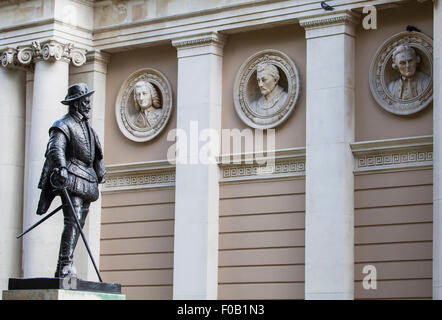 Statue von Sir Walter Raleigh mit Büsten von berühmten Persönlichkeiten der Royal Navy im Hintergrund. Stockfoto