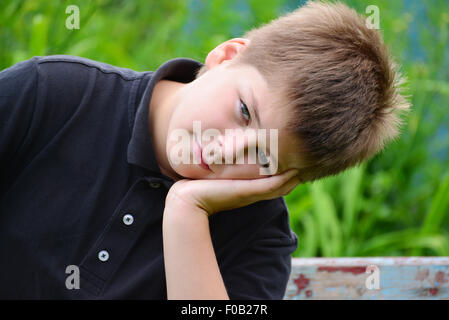 Ein Teenage Junge sitzt auf einer Bank Stockfoto