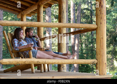 Paar genießt ein Glas Wein auf der Veranda ein Blockhaus in Minam River Lodge in Oregon Wallowa Mountains. Stockfoto
