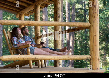 Paar genießt ein Glas Wein auf der Veranda ein Blockhaus in Minam River Lodge in Oregon Wallowa Mountains. Stockfoto