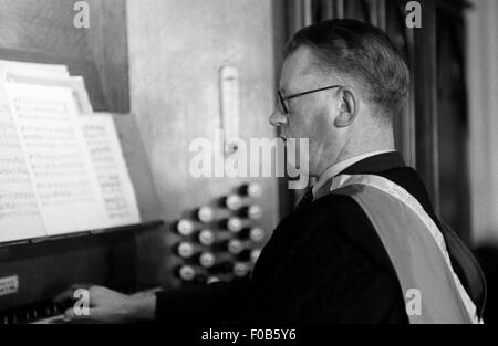Ein elegant gekleideter Mann in Roben der Orgel in der Kapelle. Stockfoto