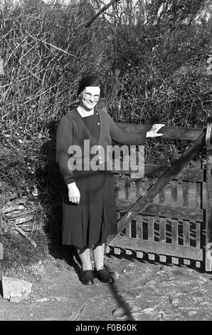 Eine Frau mittleren Alters in einem Kleid steht an einem Tor Stockfoto