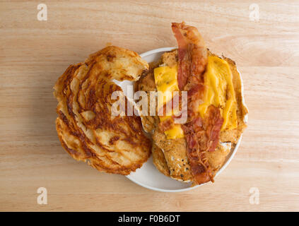Eine offene konfrontiert Speck Ei und Käse Croissant Frühstück Sandwich auf einen kleinen Teller auf einer hölzernen Tischplatte Stockfoto