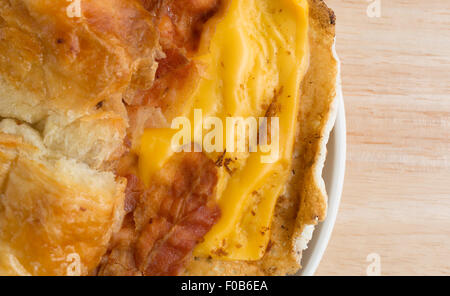 Draufsicht eines Speck Ei und Käse Croissant Frühstück Sandwiches auf einen kleinen Teller auf einer hölzernen Tischplatte in der Nähe Stockfoto