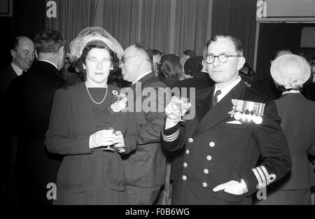 Eine elegant gekleidete Frau und ein Mann in Uniform, Offizier der Royal Navy mit seiner Medaillen auf dem Display auf einer party Stockfoto