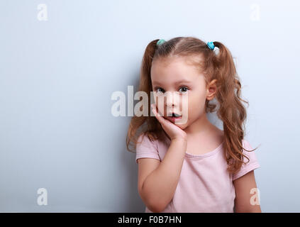 Süße lustige Kind Mädchen überraschend mit offenem Mund auf blauem Hintergrund Stockfoto