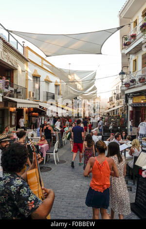 Touristen in der Straße im andalusischen weißen Dorf Nerja bedeckt mit Schatten Sonnenschutz, Sommerabend, Malaga, Spanien. Stockfoto
