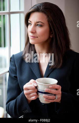 Professionelle Geschäftsfrau hält Kaffeetasse suchen nachdenklich Stockfoto