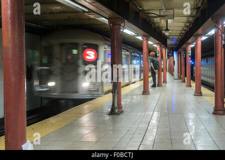 U-Bahn-Fahrer warten auf die Ankunft eines Zuges Nummer "3" an die 110 Straße Station auf der New Yorker u-Bahn auf Sonntag, 9. August 2015. (© Richard B. Levine) Stockfoto