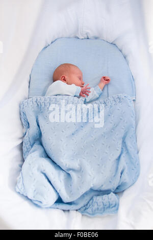 Neugeborenes Baby junge im Bett. Neues Kind geboren, unter einer blauen gestrickte Decke schlafen. Kinder schlafen. Bettwäsche für Kinder. Stockfoto