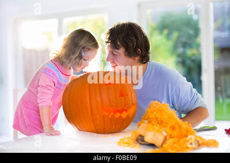 Familie schnitzen Kürbis zu Halloween. Eltern und Kinder schmücken das Haus. Kinder und Eltern Süßes oder Saures. Stockfoto