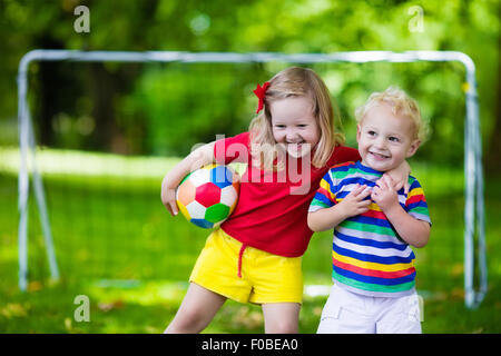Zwei glückliche Kinder spielen Fußball im Freien im Schulhof. Kinder spielen Fußball. Aktiv Sport für Vorschulkind. Stockfoto