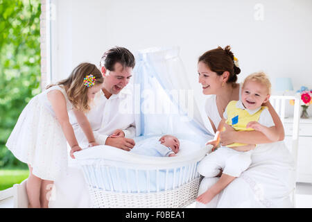 Große Familie mit vier Kindern in weiße Schlafzimmer. Eltern und Kinder stehen an der Krippe des Neugeborenen Baby boy Stockfoto