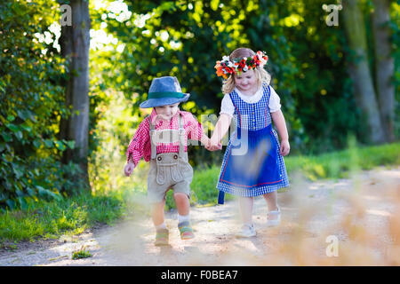 Kinder in bayerischer Tracht im Weizenfeld. Deutsche Kinder essen Brot und Brezel während Oktoberfest in München. Bro Stockfoto