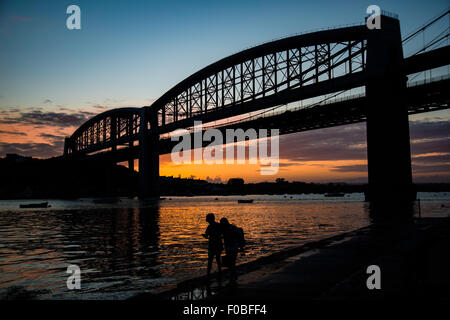 Zwei jungen Heimweg entlang des Flussufers nach einem Tag beim Angeln mit der Albert Bridge und Sonnenuntergang im Hintergrund. Stockfoto