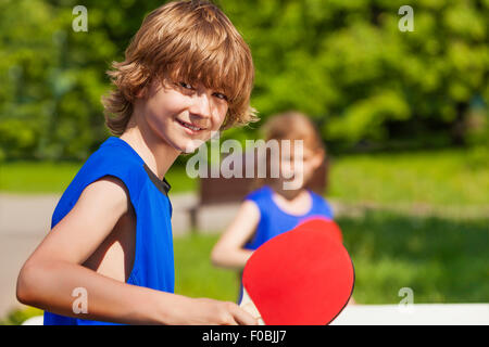 Jungen und Mädchen zusammen spielen Ping-Pong außerhalb Stockfoto