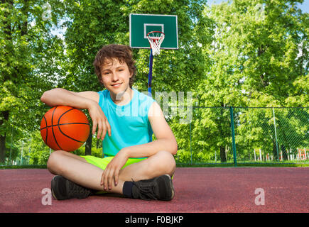 Junge sitzt alleine mit Ellenbogen am ball Stockfoto