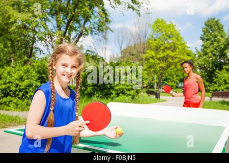 Zwei glückliche Mädchen spielen Pingpong außerhalb Stockfoto