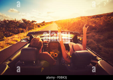 Glückliches junges Paar Fahrt entlang der Landstraße im Cabrio bei Sonnenuntergang. Freiheit Abenteuer Roadtrip! Stockfoto