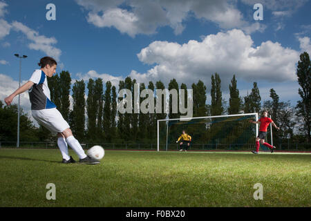 Voller Länge des jungen Fußballer treten Ball in Richtung Tor Stockfoto