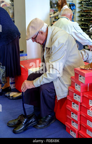 Alter Mann, der versucht, auf neue Schuhe im Shop. Stockfoto