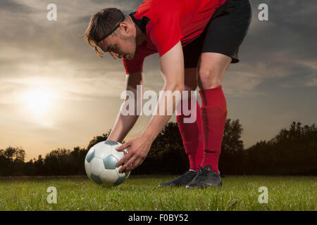 Voller Länge des jungen Fußballer Ball auf Feld positionieren Stockfoto