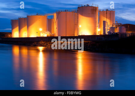 Kraftstofftanks auf der Bank des Flusses nachts beleuchtet Stockfoto